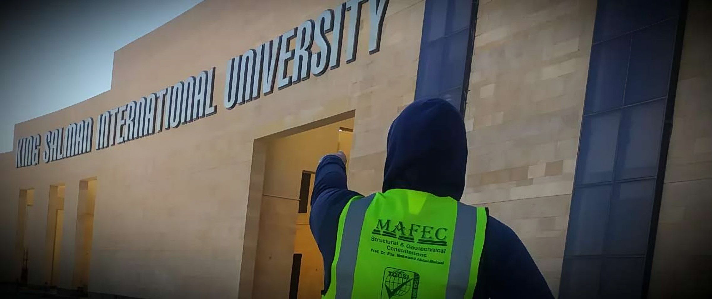 A MAFEC engineer in a site vest points at the entrance of King Salman International University.